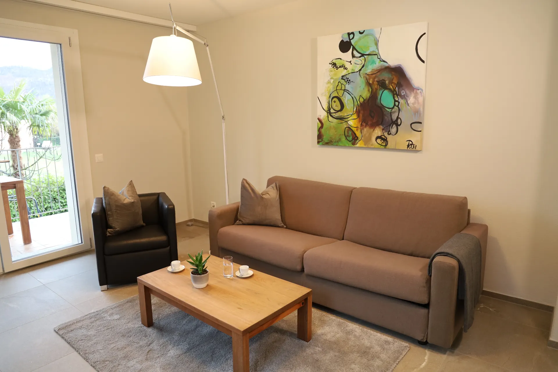Maggia Wohnbereich mit Sofa, Sessel und Balkonzugang