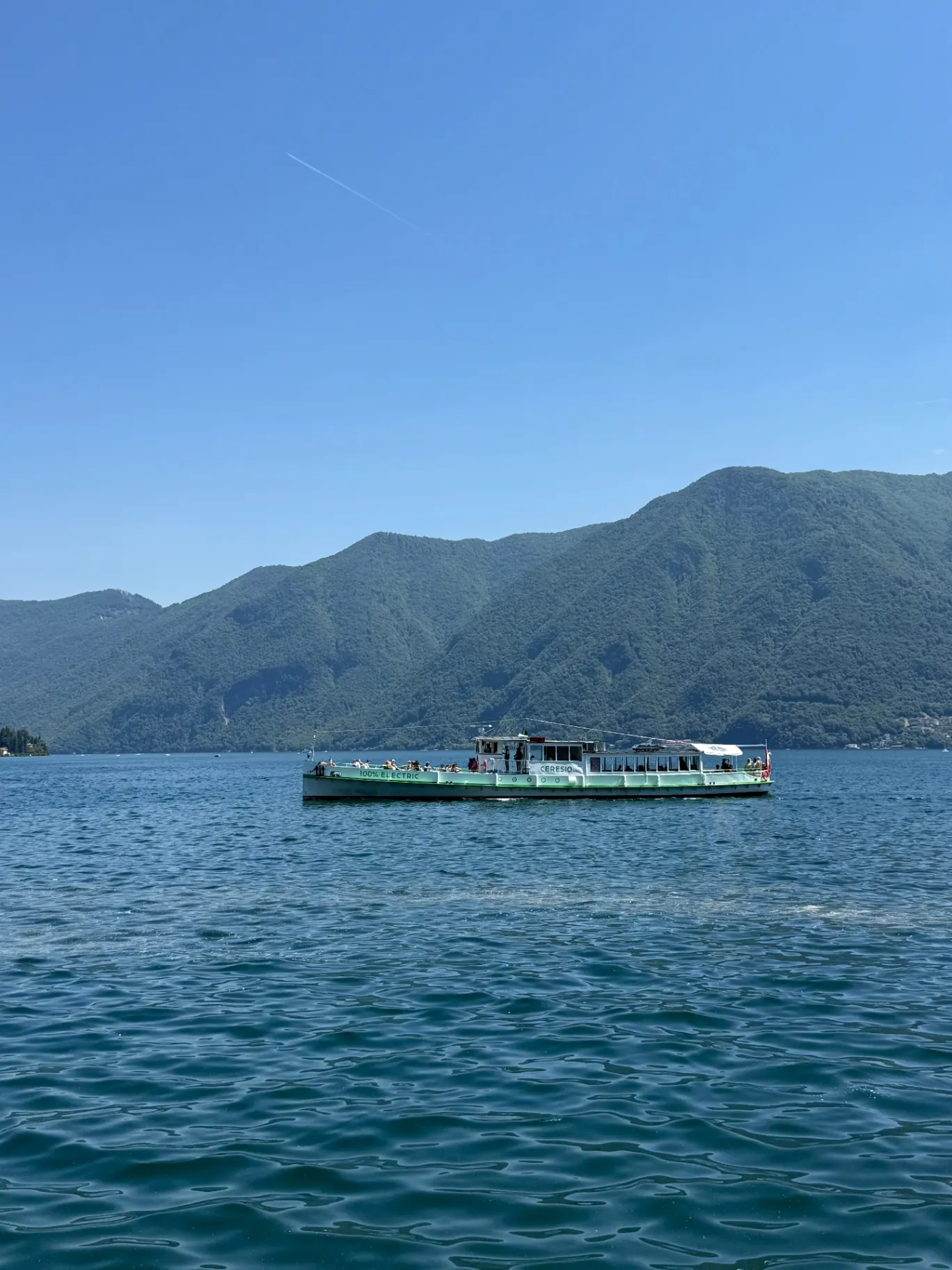 Ausflugsschiff auf dem Luganersee vor bewaldeten Bergen
