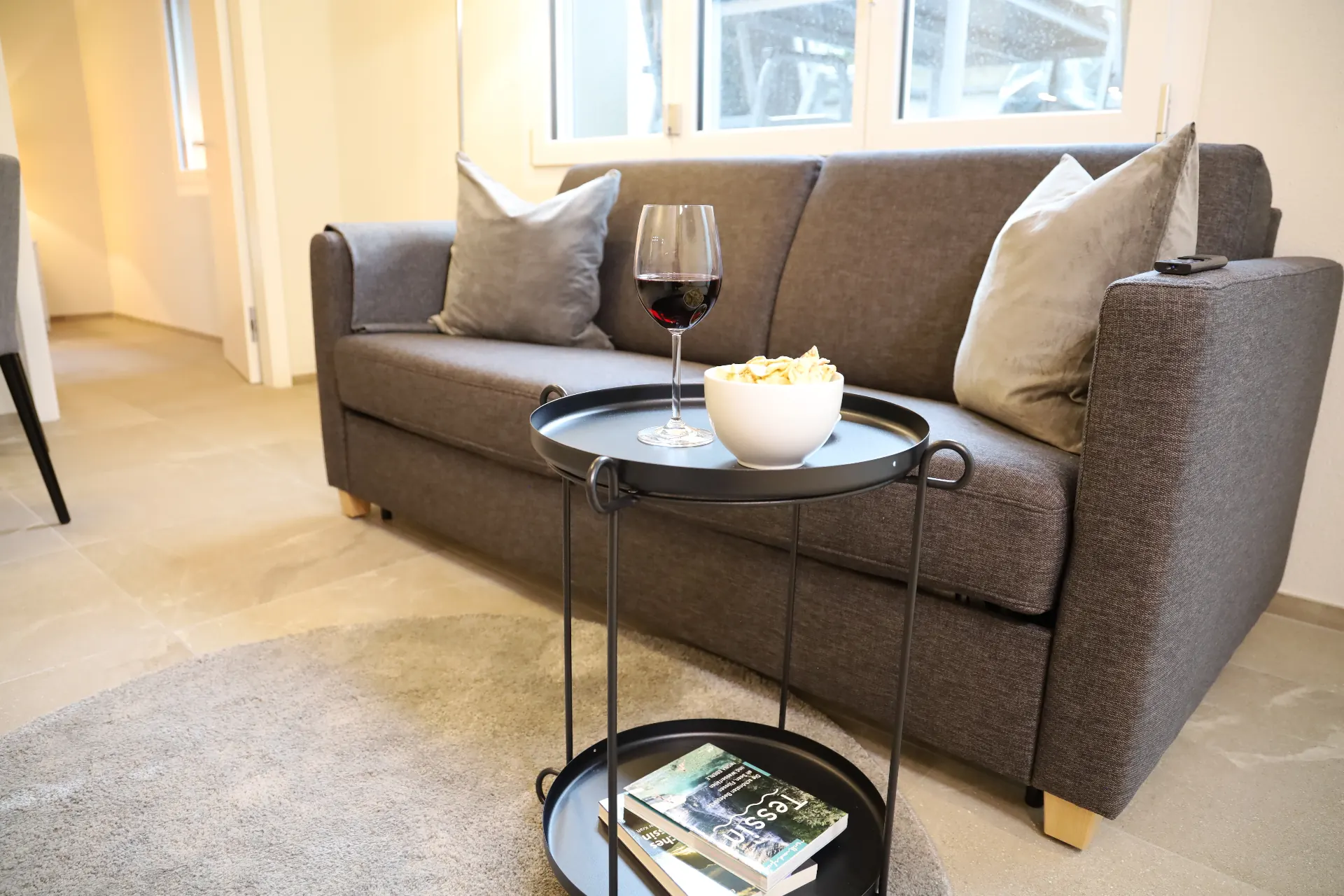 Isorno Wohnbereich mit Sofa, Fensterfront und Beistelltisch