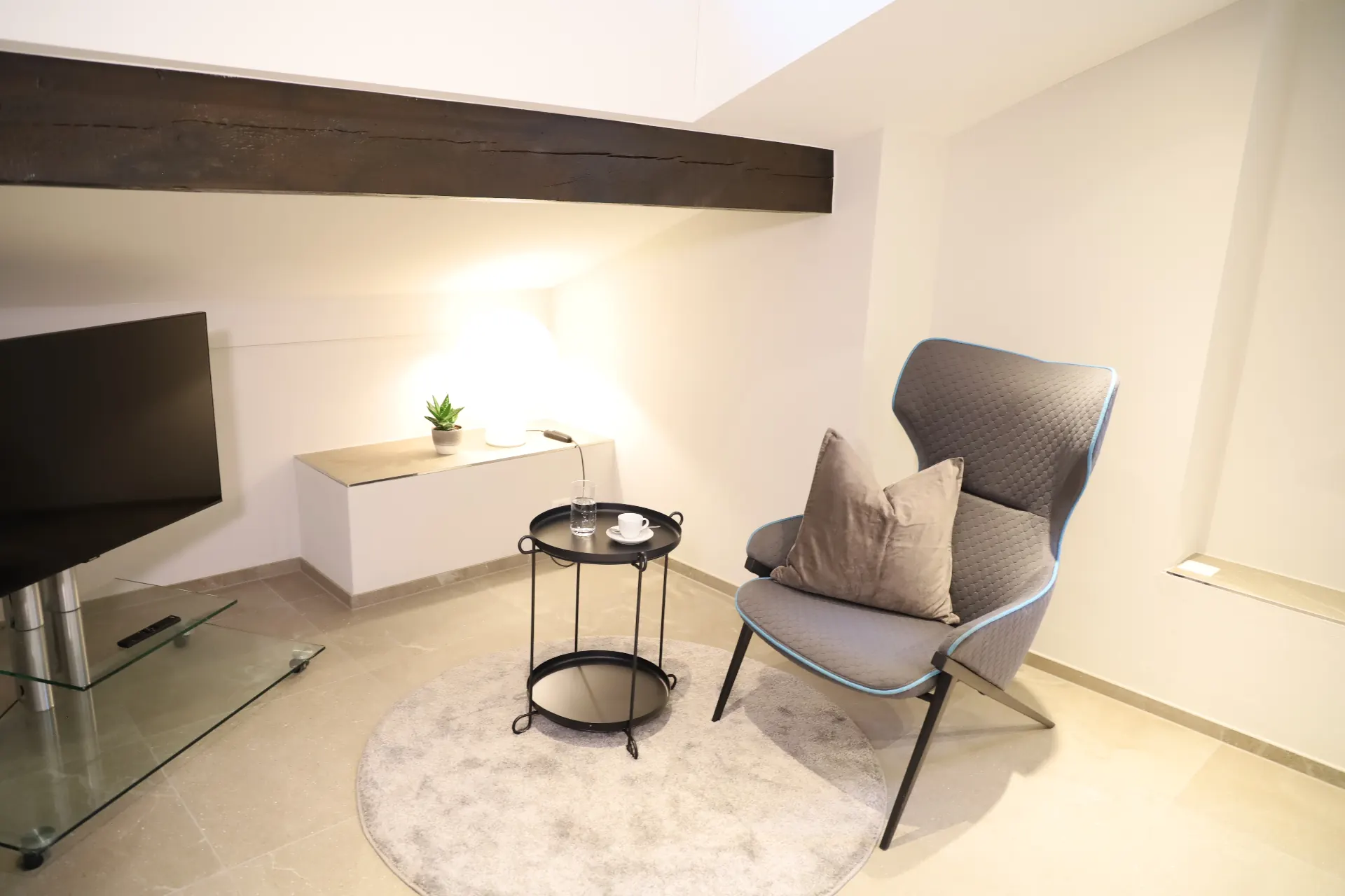 Verzasca Loungebereich mit Sessel, TV und Holzbalken