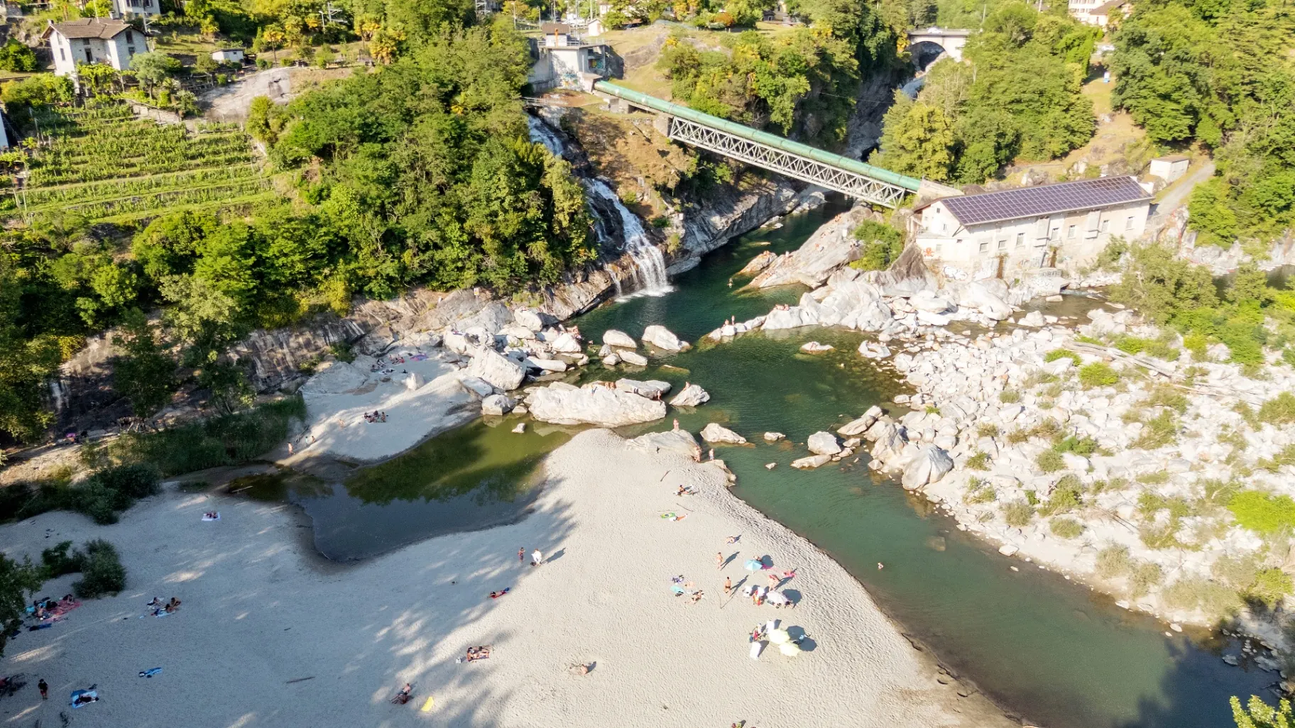 Luftaufnahme von Flussstrand, Wasserfall und Brücke bei Ponte Brolla