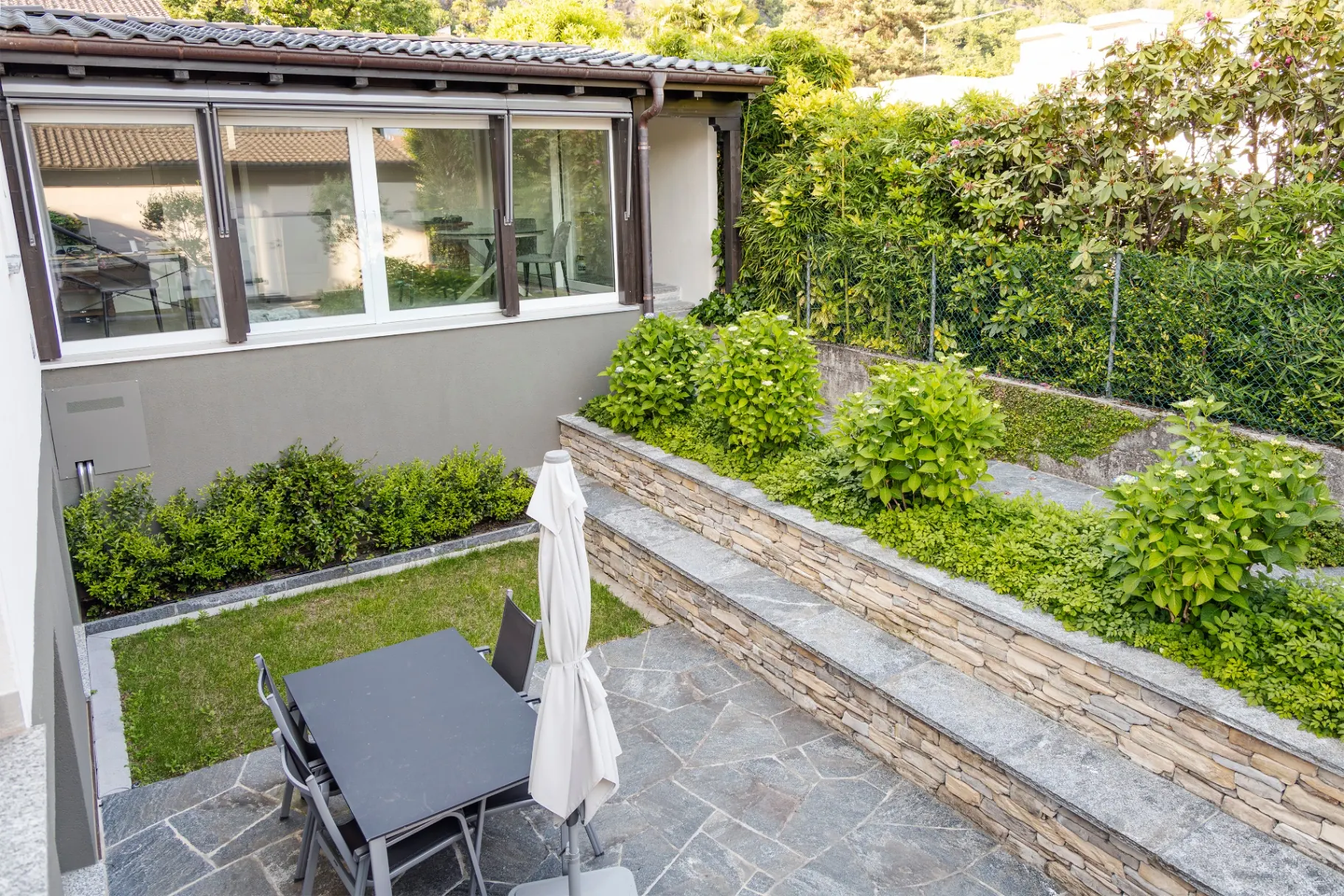 Isorno Garten mit Rasen, Hortensien und Steinmauern