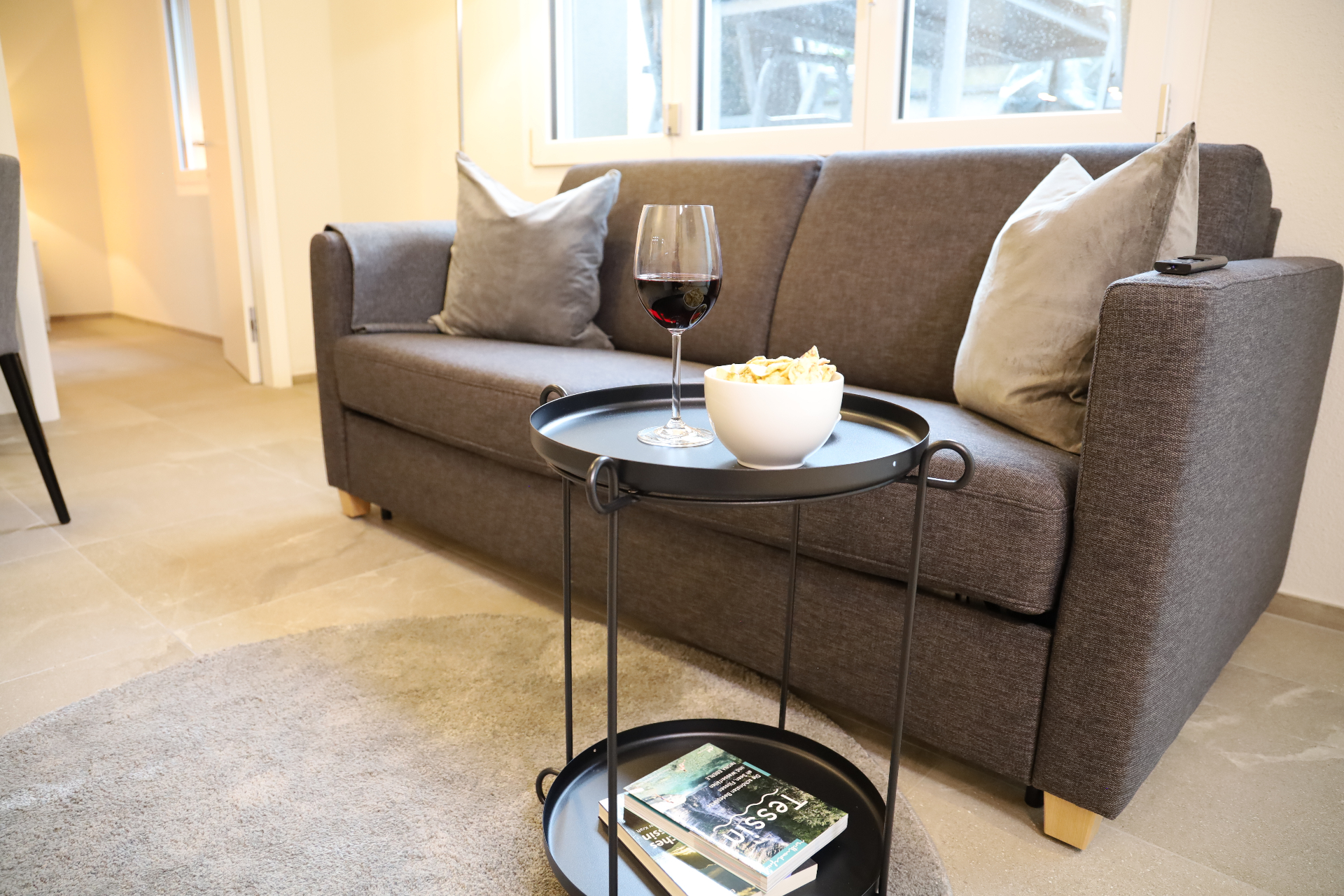 Isorno Wohnbereich mit Sofa, Fensterfront und Beistelltisch