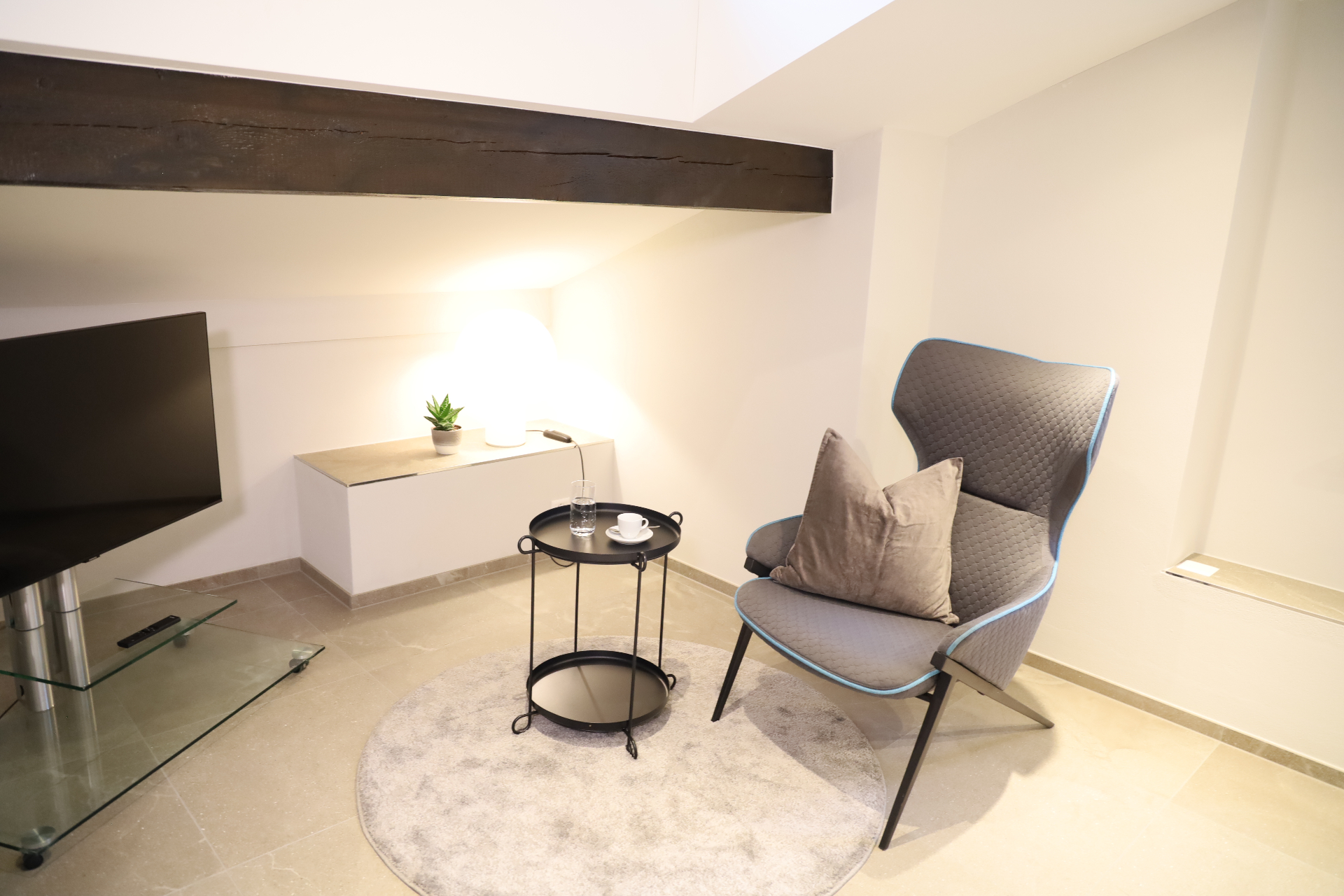 Verzasca Loungebereich mit Sessel, TV und Holzbalken