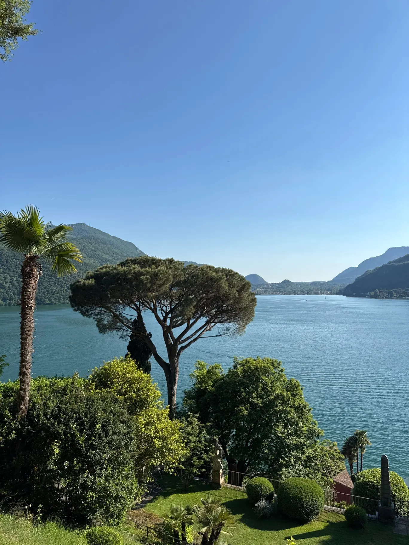 Panoramablick über den Luganersee mit mediterranen Bäumen